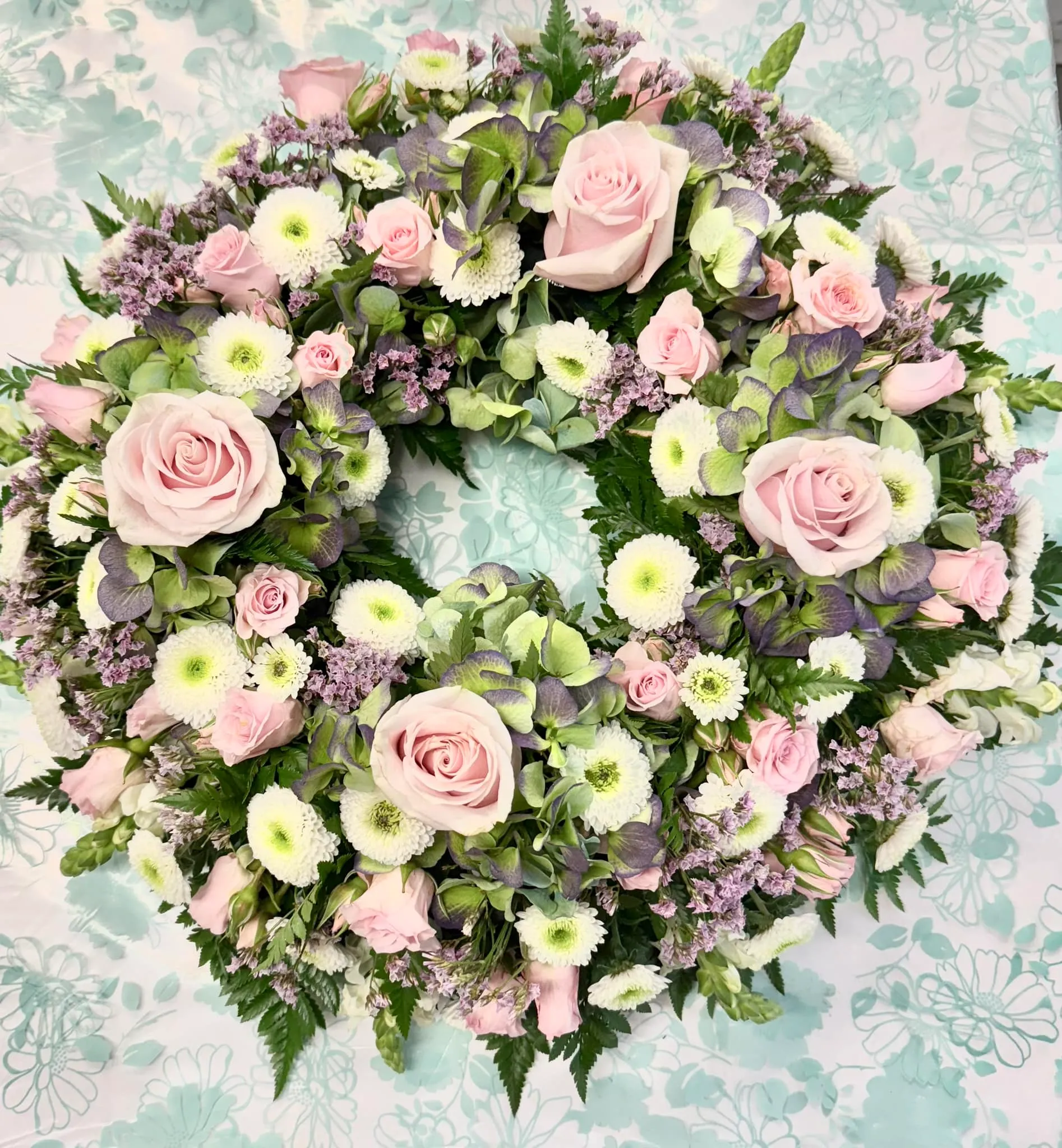 A wreath of pink and white flowers on a table.