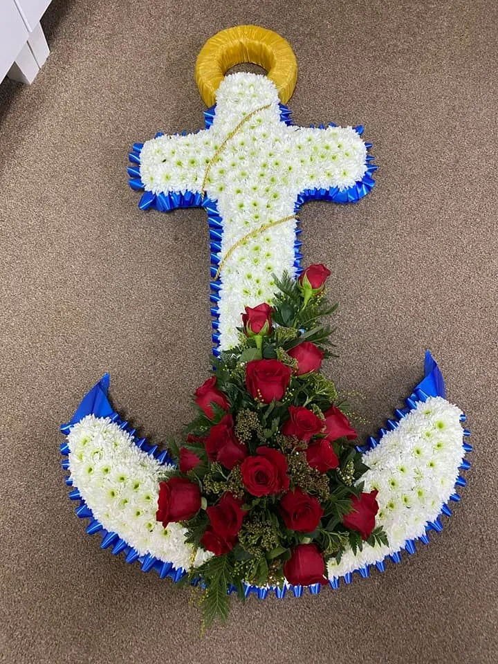A cross made out of flowers on the ground.