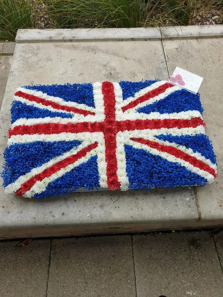 A cake shaped like the british flag on a sidewalk.