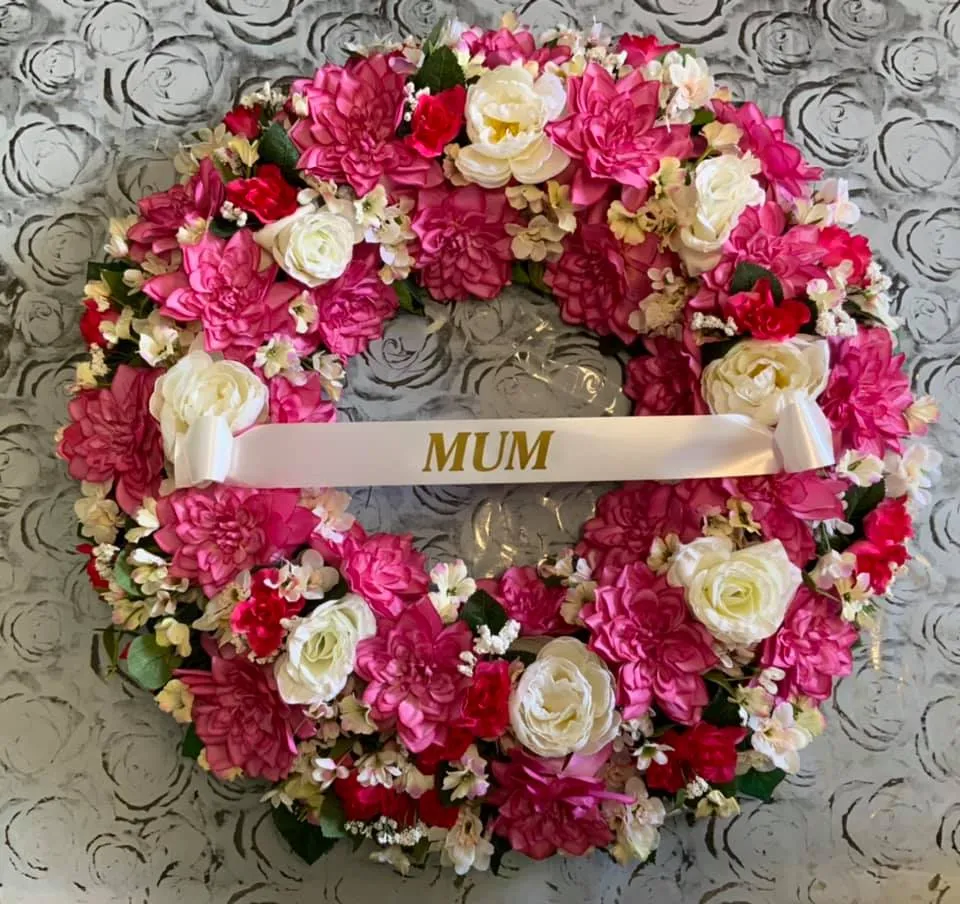 A pink and white wreath with the word mum on it.