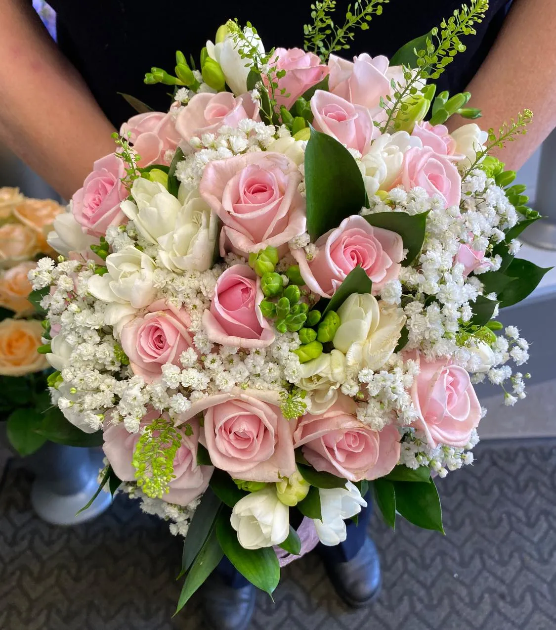A bouquet of pink and white flowers in a woman's hand.